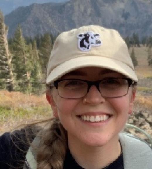 Elli on a hike wearing a UC Davis cap with a cow on it