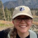 Elli on a hike wearing a UC Davis cap with a cow on it